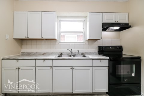 A kitchen with white cabinets and a black stove top oven.