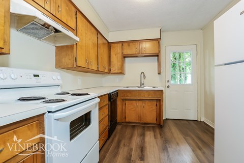 A kitchen with wooden cabinets and a white stove.