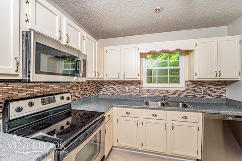 A kitchen with a black stove top oven and a black microwave above it.