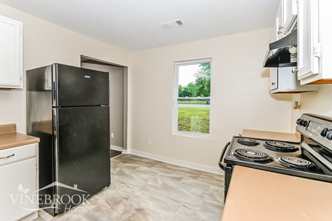 A kitchen with a black fridge and stove top oven.
