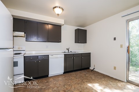 A kitchen with black cabinets and a white fridge.