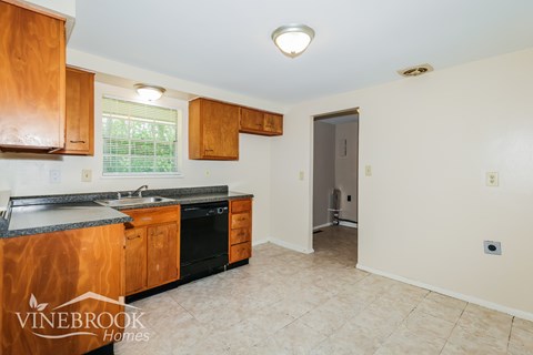 A kitchen with wooden cabinets and a black dishwasher.