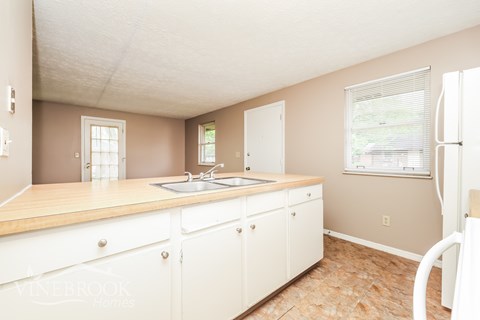 A kitchen with white cabinets and a wooden countertop.