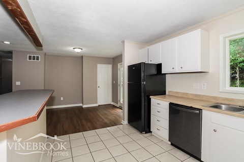A kitchen with a black refrigerator and white cabinets.