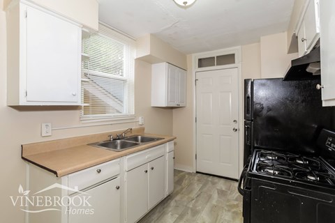 A kitchen with white cabinets and a black stove.