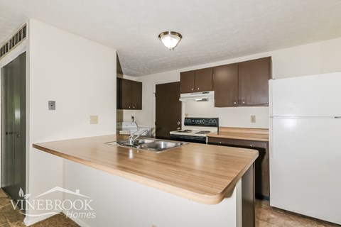 A kitchen with a white refrigerator and brown cabinets.