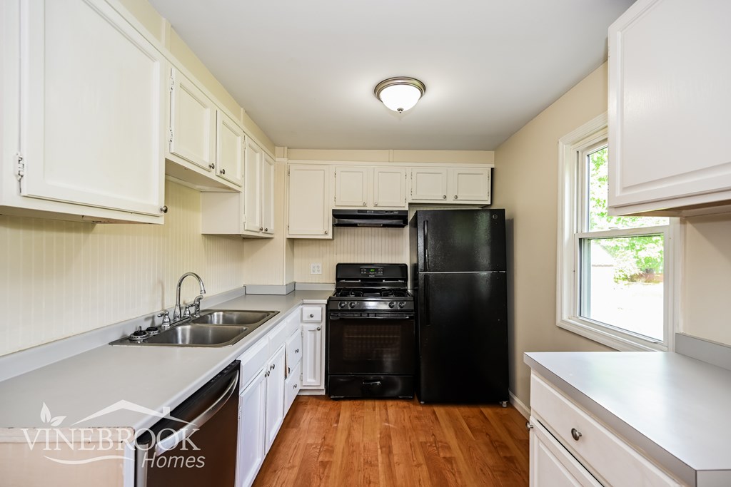 A kitchen with white cabinets and a black fridge.