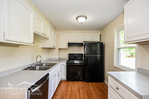 A kitchen with white cabinets and a black fridge.