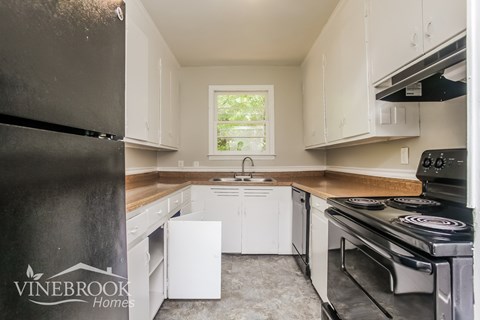 A kitchen with a black refrigerator and white cabinets.