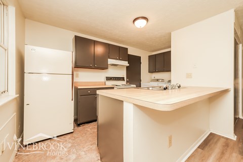 A kitchen with a white fridge and a white island.