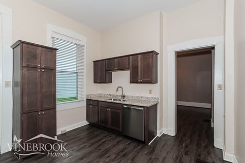 A kitchen with dark wood cabinets and a white sink.