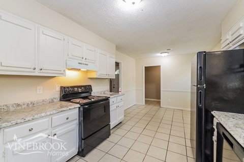 A kitchen with white cabinets and black appliances.