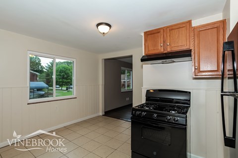 A kitchen with a black stove top oven and wooden cabinets.