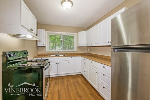 A kitchen with white cabinets and a Vinebrook Homes sign.