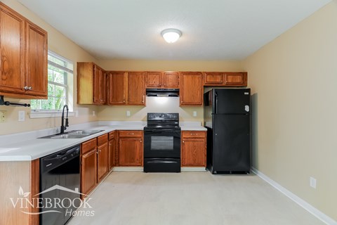 A kitchen with wooden cabinets and black appliances.