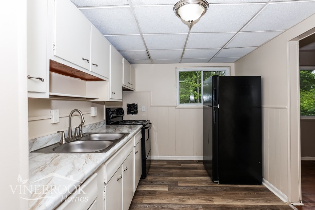 A kitchen with white cabinets and a black refrigerator.