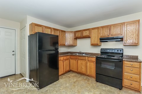 A kitchen with wooden cabinets and black appliances.