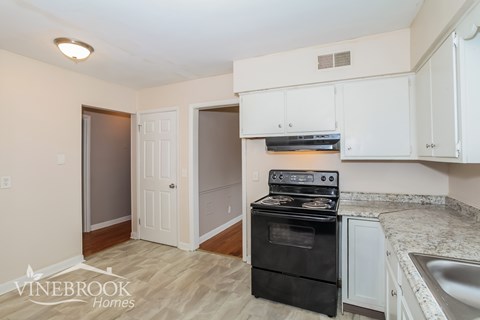 A kitchen with a black stove top oven and white cabinets.