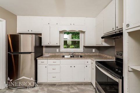A kitchen with white cabinets and a stainless steel refrigerator.