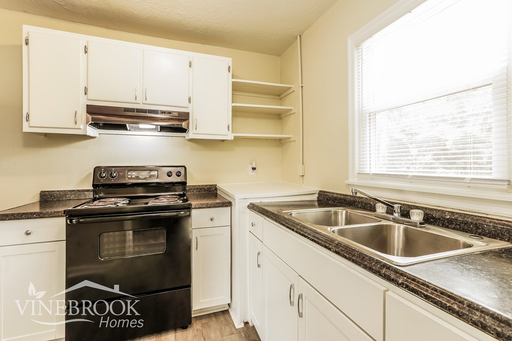 A kitchen with a black stove top oven and white cabinets.