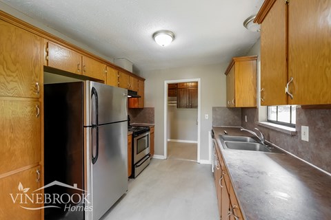 A kitchen with wooden cabinets and a stainless steel refrigerator.