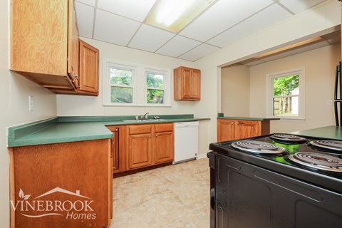 A kitchen with wooden cabinets and a Vinebrook Homes logo.