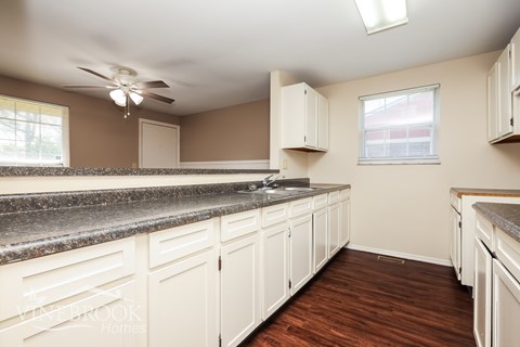 A kitchen with white cabinets and a marble countertop.