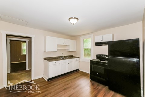 A kitchen with a black fridge and white cabinets.