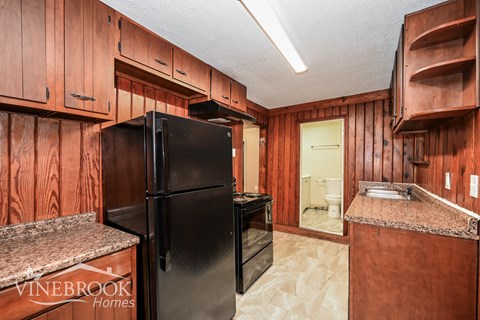 A kitchen with wooden cabinets and a black refrigerator.