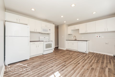 A kitchen with white appliances and cabinets.