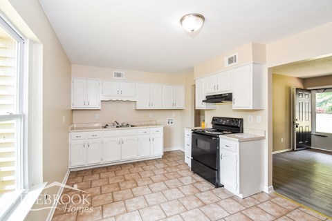 A kitchen with white cabinets and a black stove top oven.