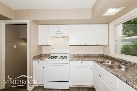 A kitchen with white cabinets and a granite countertop.