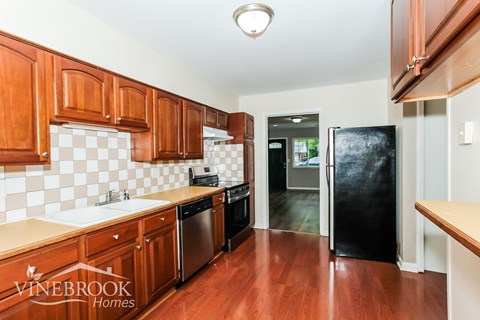 A kitchen with wooden cabinets and a black fridge.