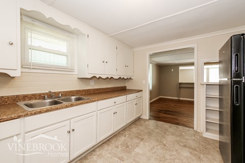A kitchen with white cabinets and a black refrigerator.