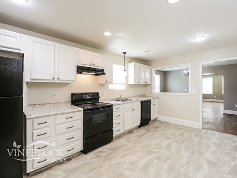 A kitchen with white cabinets and black appliances.