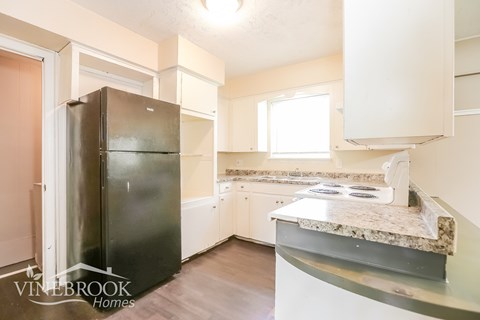 A kitchen with a black fridge and a counter top with a stove on it.