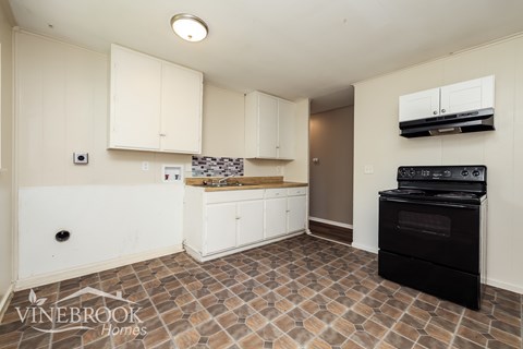 A kitchen with a black oven and white cabinets.