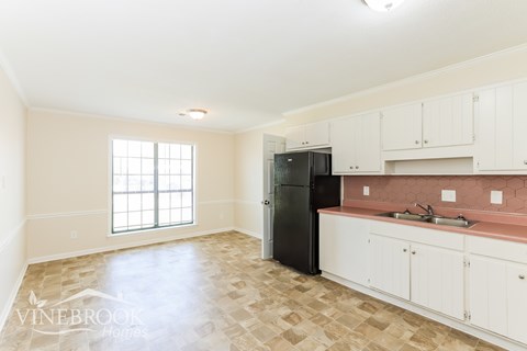 A kitchen with a black refrigerator and white cabinets.