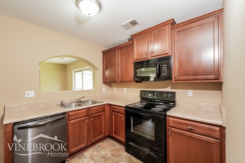 A kitchen with wooden cabinets and a black stove top oven.