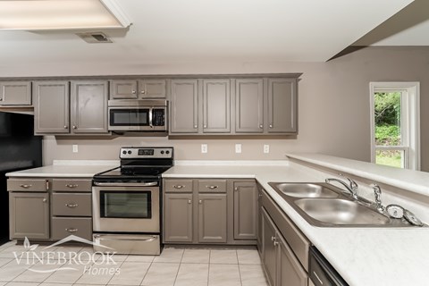 A kitchen with a black stove top oven and a microwave above the stove.
