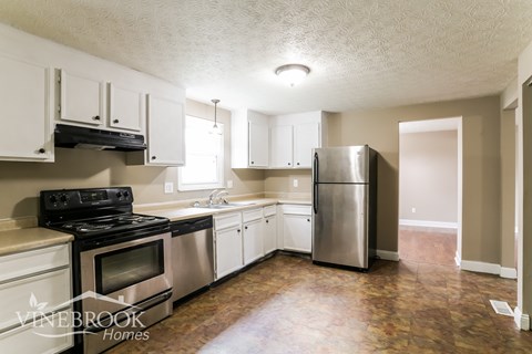 A kitchen with a stove top oven and a refrigerator.