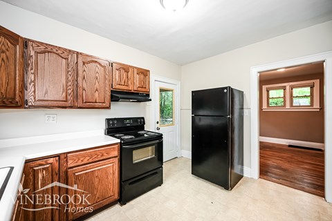 A kitchen with wooden cabinets and black appliances.