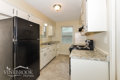 A kitchen with a black fridge and white cabinets.