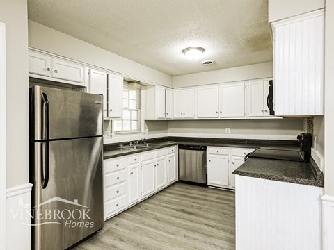 A kitchen with a stainless steel refrigerator and white cabinets.