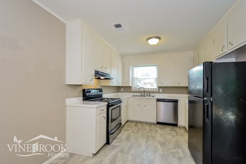 A kitchen with white cabinets and black appliances.