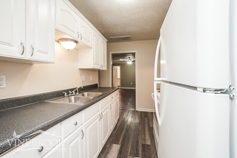 A kitchen with white cabinets and a black countertop.