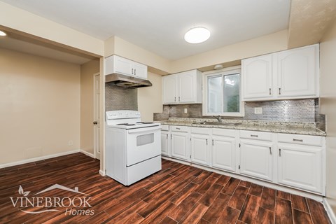 A kitchen with white cabinets and a wooden floor.