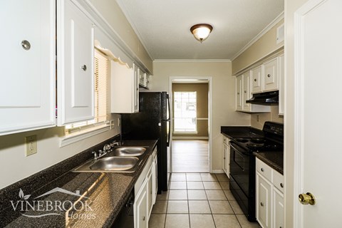 A kitchen with black appliances and white cabinets.