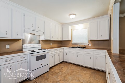 A kitchen with white cabinets and a stove top oven.