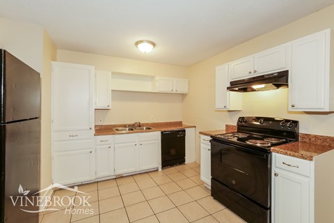 A kitchen with white cabinets and black appliances.